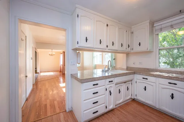 an empty room with a chandelier fan and windows