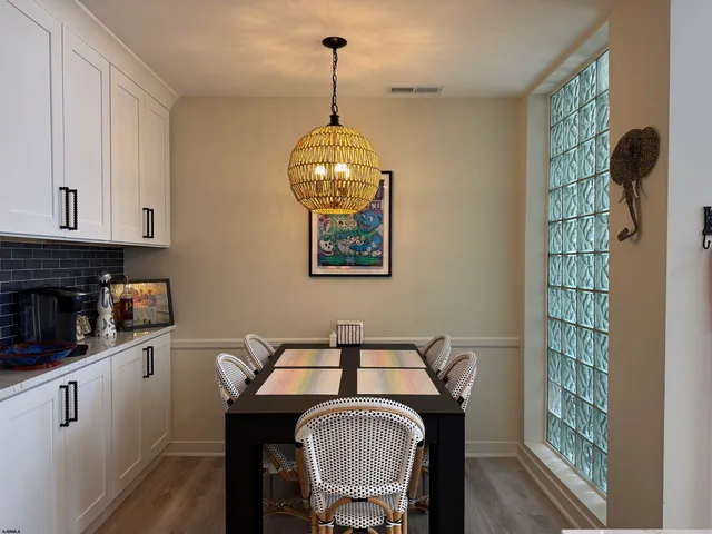 a kitchen with stainless steel appliances granite countertop a stove a oven a white table and chairs with wooden floor