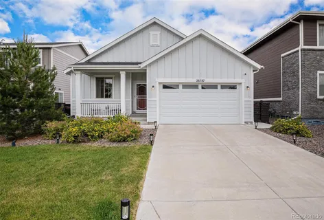a view of a white house next to a yard with plants