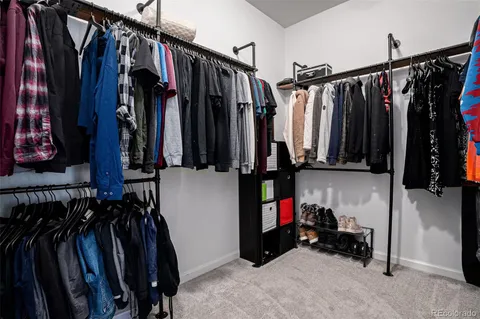 a view of walk in closet with clothes and shoes