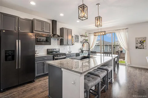 a kitchen with kitchen island granite countertop a sink a counter space stainless steel appliances cabinets and wooden floor