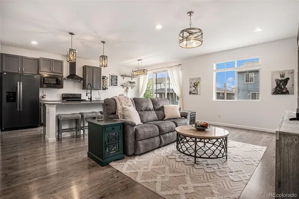 a living room with furniture a refrigerator and a kitchen view