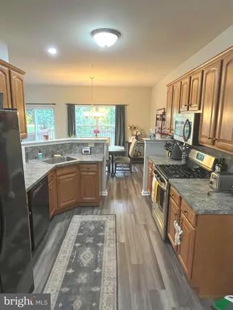 a kitchen with stainless steel appliances granite countertop a refrigerator stove sink and wooden floor