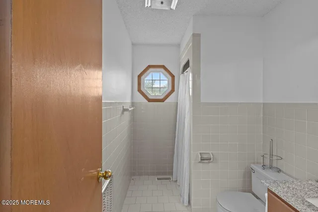 a bathroom with a granite countertop toilet and a shower