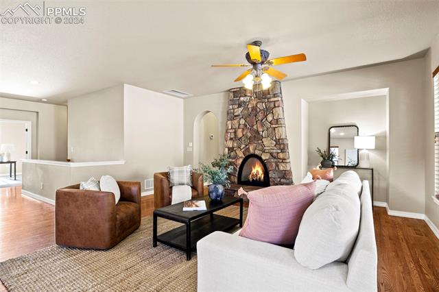 2464 Cinnabar Road Colorado Springs, CO 80921 - Photo 11 of 43 Living room with a stone fireplace, ceiling fan, and hardwood / wood-style floors