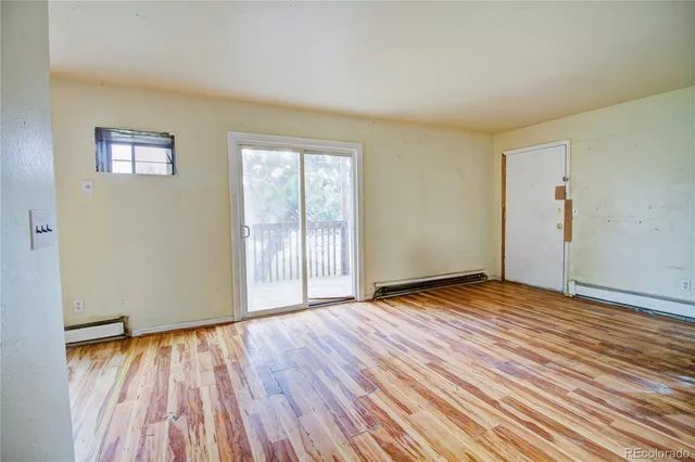 a view of an empty room with wooden floor and a window