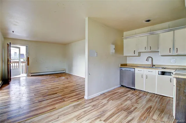 a kitchen with wooden floors white cabinets and stainless steel appliances