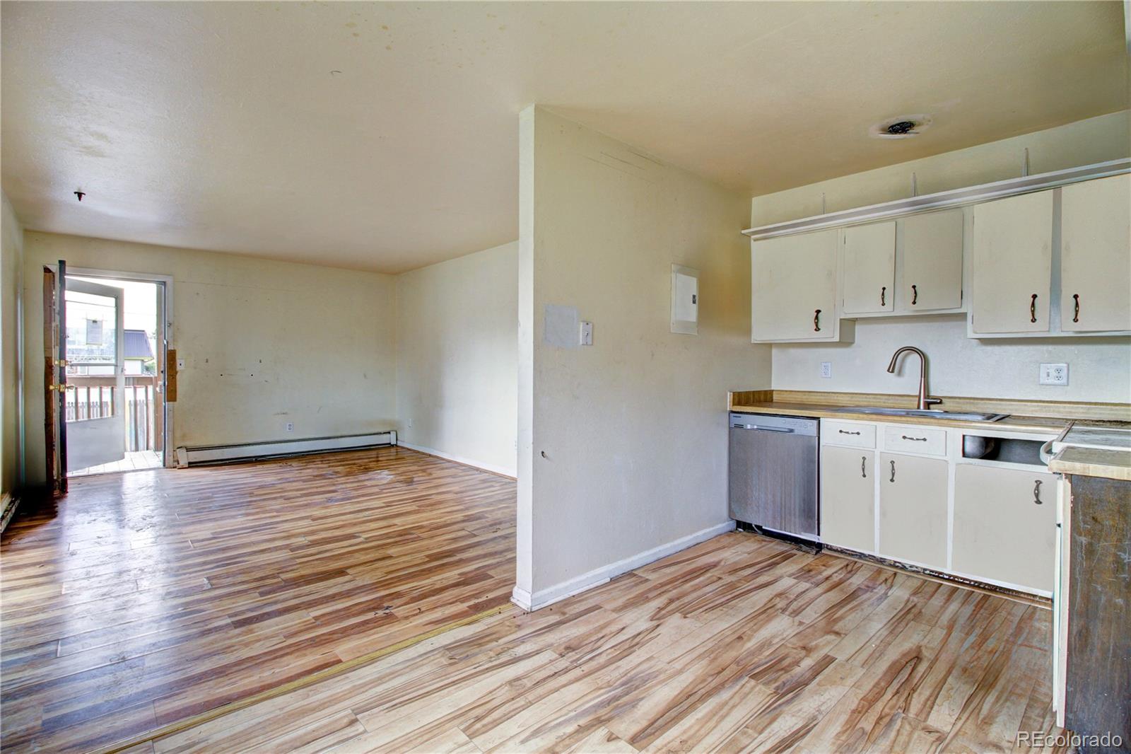 9340 West 49th Avenue, Unit 213 Wheat Ridge, CO 80033 - Photo 5 of 16 a kitchen with wooden floors white cabinets and stainless steel appliances