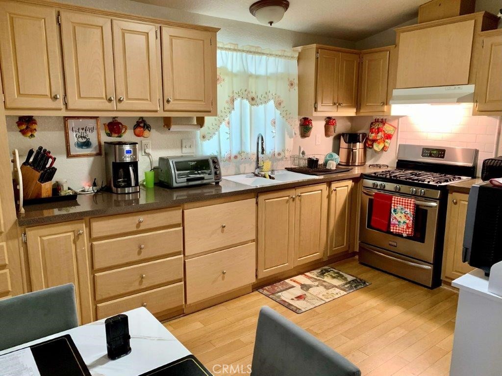 33600 Calimesa Boulevard, Unit 141 Yucaipa, CA 92399 - Photo 3 of 23 a kitchen with stainless steel appliances granite countertop a stove a sink dishwasher and cabinets with wooden floor