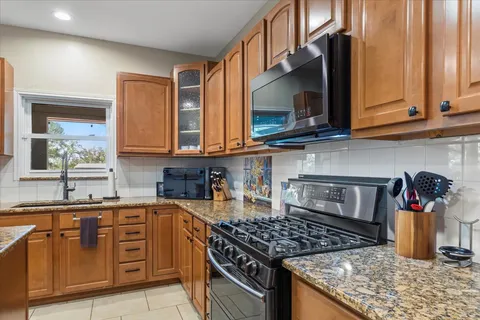 a kitchen with stainless steel appliances granite countertop a stove a sink and a microwave