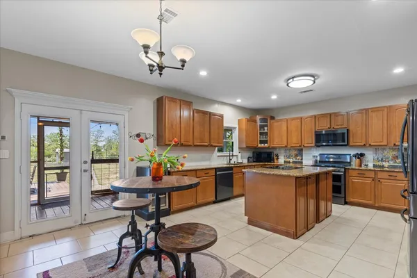 a kitchen with stainless steel appliances granite countertop a stove top oven a sink dishwasher a dining table and chairs with wooden floor