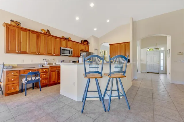 a view of kitchen with stainless steel appliances kitchen island granite countertop dining table chairs and a stove top oven