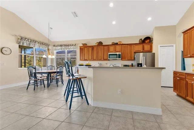 a dining room filled a chandelier and kitchen view
