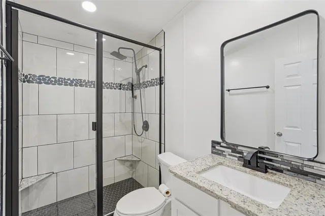 a bathroom with a granite countertop sink toilet and shower