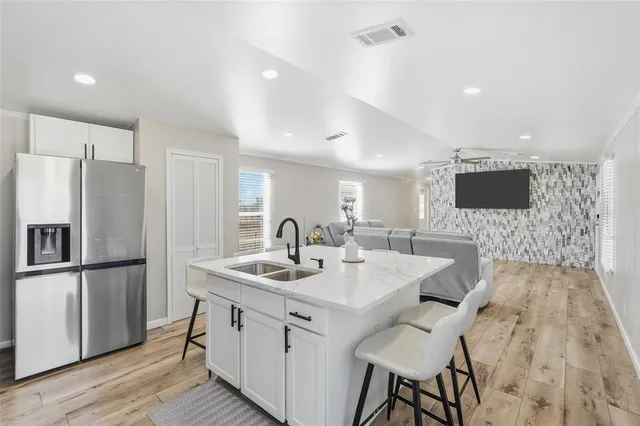 a kitchen with a sink stainless steel appliances and wooden floor