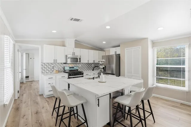 a kitchen with stainless steel appliances kitchen island granite countertop a dining table chairs and granite counter tops