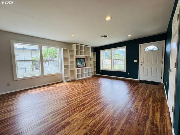 a view of an empty room with glass door and wooden floor