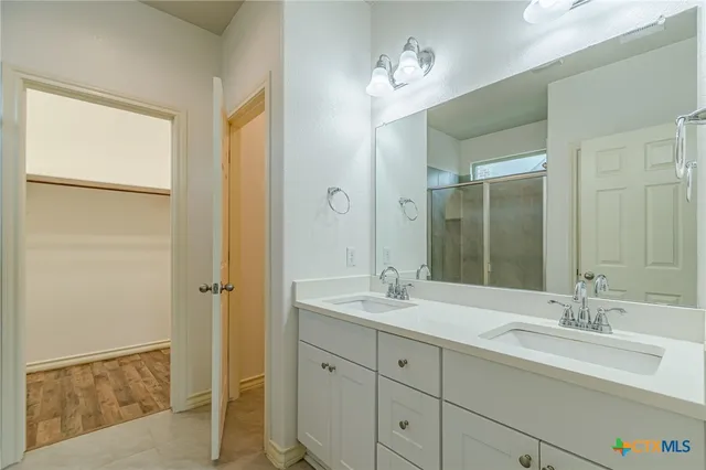 a bathroom with a double vanity sink mirror and next to a window