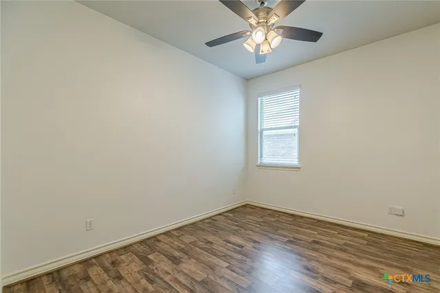 an empty room with a window and wooden floor