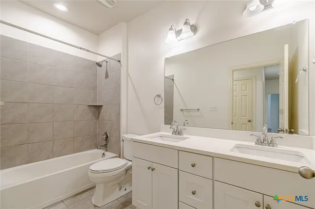 a bathroom with a double vanity sink toilet mirror and bathtub