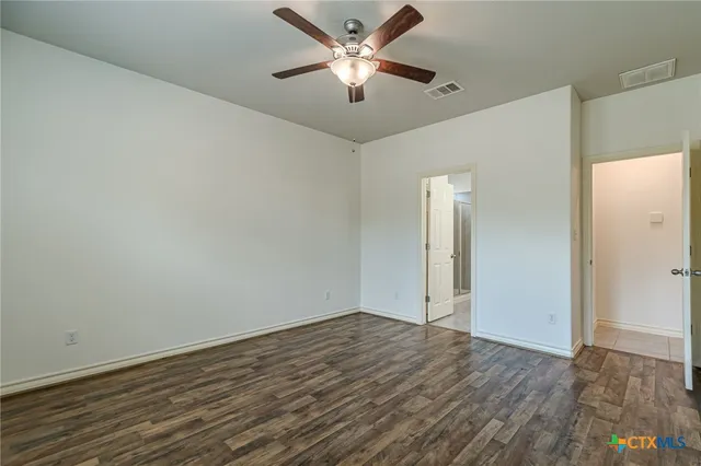 an empty room with wooden floor and a ceiling fan
