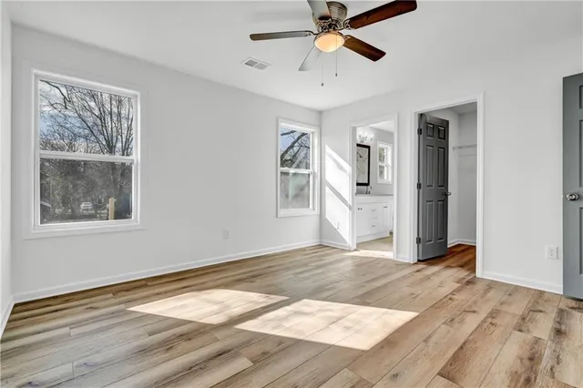 a view of an empty room with window and wooden floor