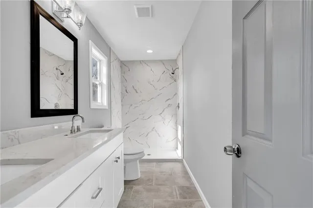 a bathroom with a double vanity sink toilet mirror and shower