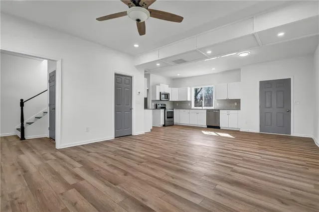 a view of a kitchen with a refrigerator a ceiling fan and wooden floor