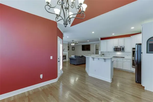 a kitchen with stainless steel appliances granite countertop a sink a microwave a refrigerator and white cabinets