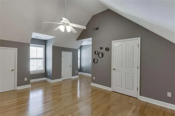 a view of empty room with wooden floor and fan