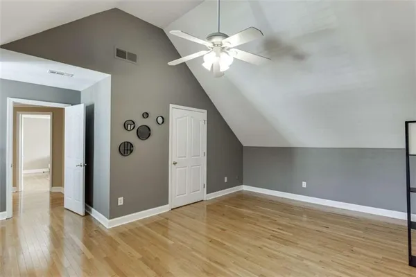 a view of empty room with wooden floor and fan