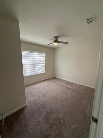 an empty room with a chandelier fan and windows