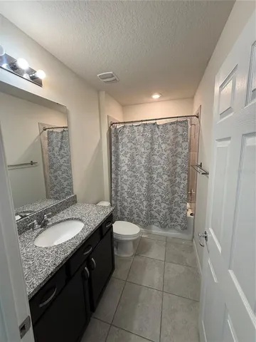 a bathroom with a granite countertop sink a toilet a mirror and shower
