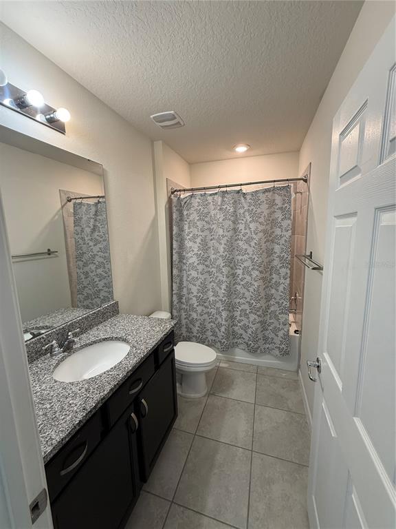 619 Citrus Isle Boulevard Davenport, FL 33837 - Photo 8 of 21 a bathroom with a granite countertop sink a toilet a mirror and shower