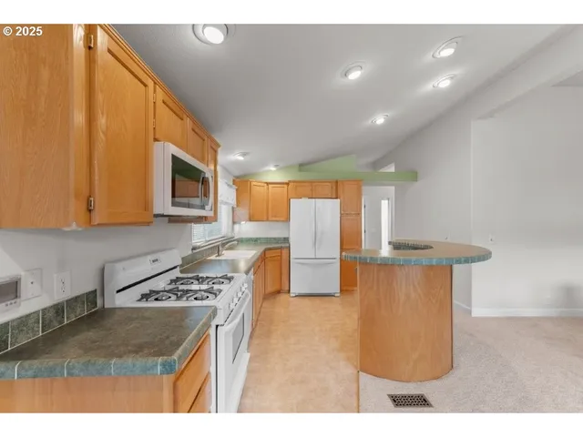a kitchen with stainless steel appliances granite countertop a sink a stove a microwave a counter top space and cabinets