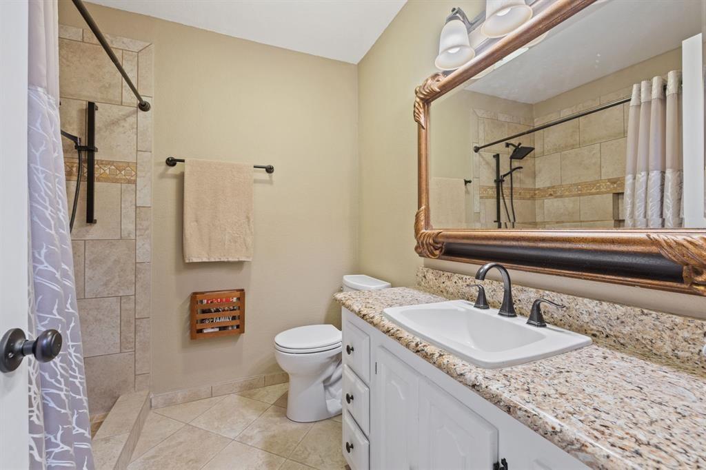 635 Old Justin Road Argyle, TX 76226 - Photo 19 of 36 a bathroom with a granite countertop sink a toilet and a shower