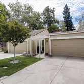 a view of a white house with a small yard and large tree