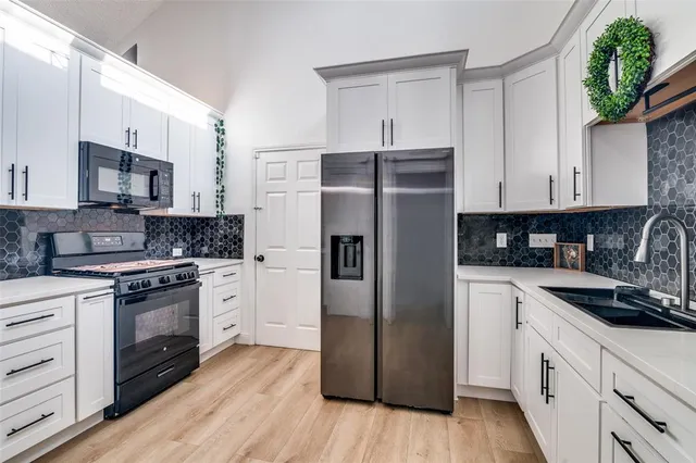 a kitchen with stainless steel appliances granite countertop a refrigerator stove and sink with wooden floor