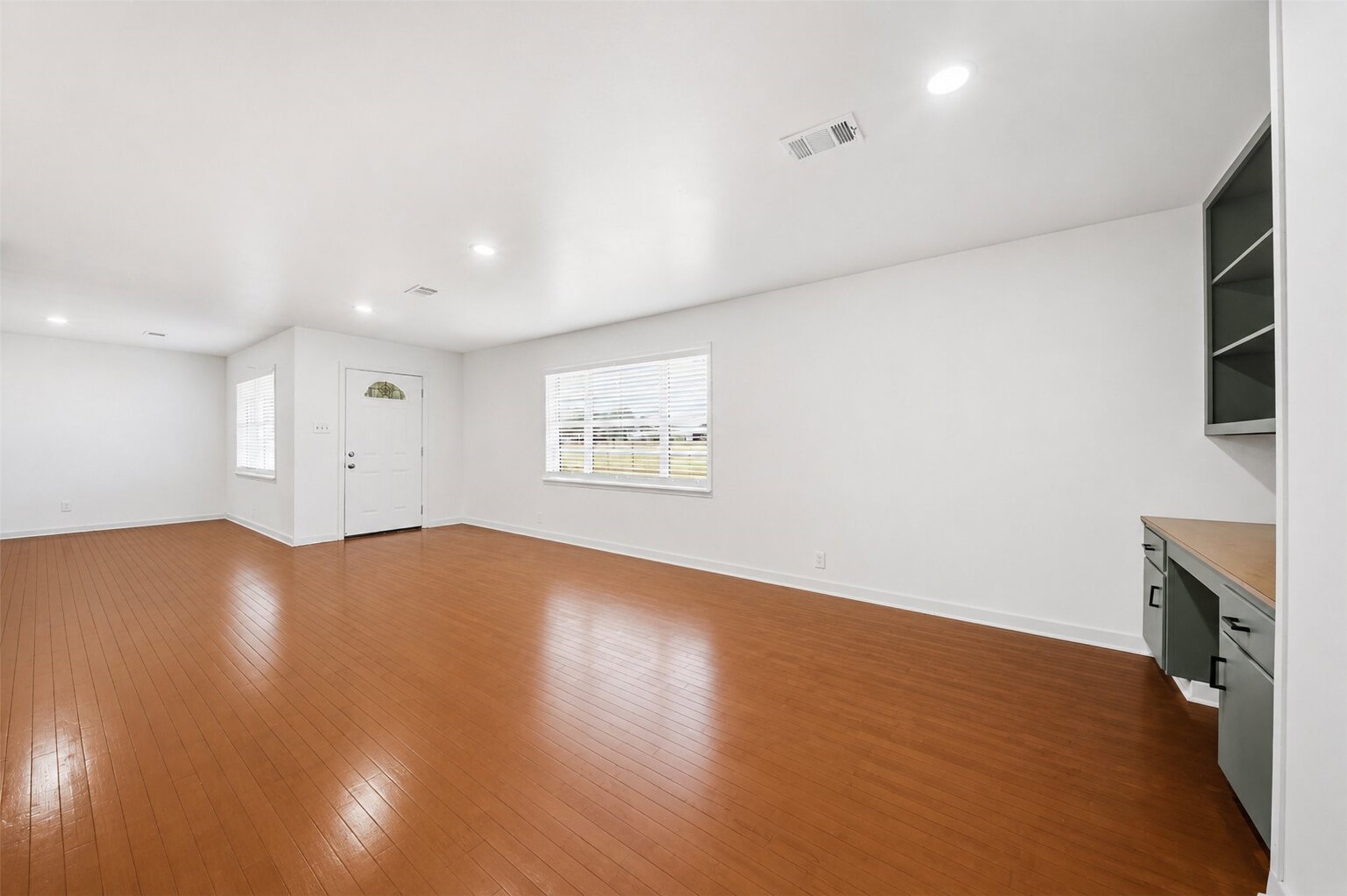 5443 Randon School Road Rosenberg, TX 77471 - Photo 4 of 20 Bright family room view featuring multiple windows, recessed lighting, wood flooring, and a built-in workspace along the wall.