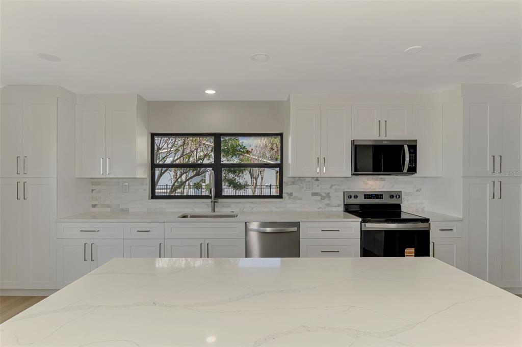 1822 Riverside Drive East Bradenton, FL 34208 - Photo 15 of 46 a kitchen with granite countertop a stove a sink and a microwave