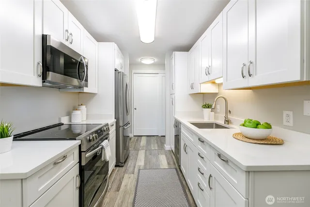a kitchen with stainless steel appliances granite countertop a sink a stove and a microwave