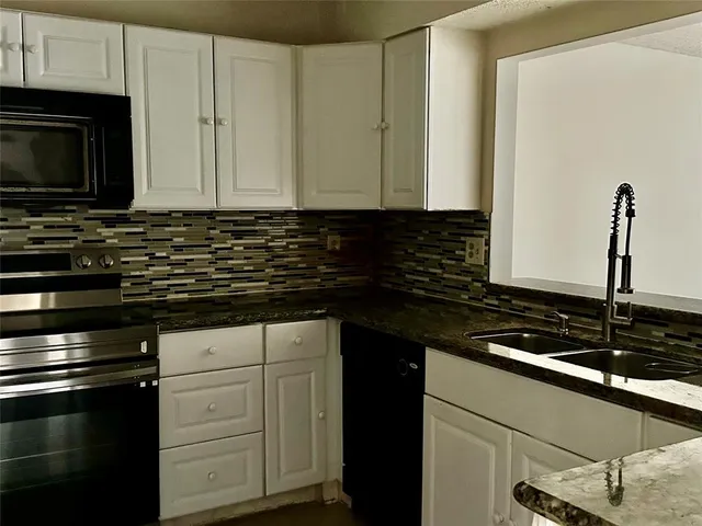 a kitchen with sink a microwave a stove and cabinets