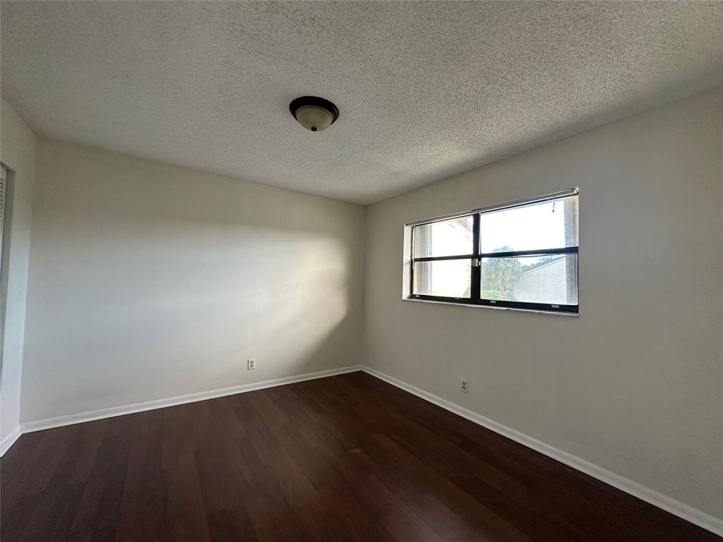 22415 Southwest 61st Way, Unit 202 Boca Raton, FL 33428 - Photo 4 of 14 an empty room with wooden floor and windows