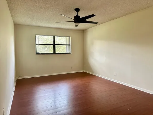 a view of room with hardwood floor and a ceiling fan