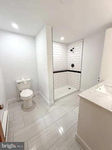 a bathroom with a granite countertop sink a toilet and a shower