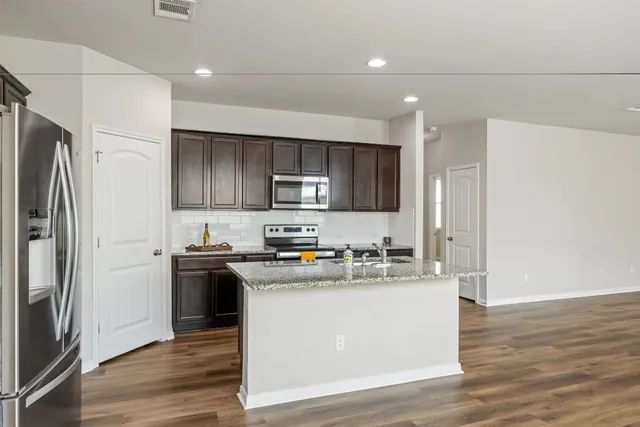 a kitchen with stainless steel appliances granite countertop a refrigerator stove microwave and sink