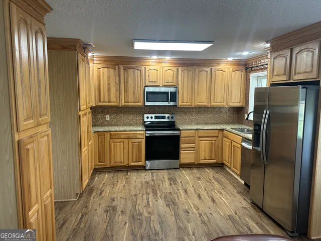 a kitchen with a refrigerator a stove top oven and cabinets