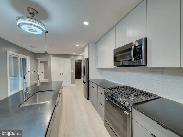 a kitchen with stainless steel appliances granite countertop a stove top oven a sink dishwasher a dining table and chairs with wooden floor