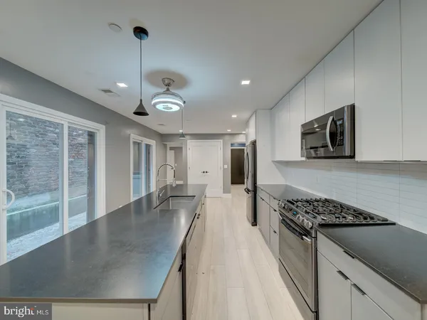 a kitchen with stainless steel appliances granite countertop a stove a sink dishwasher a refrigerator and a dining table with wooden floor