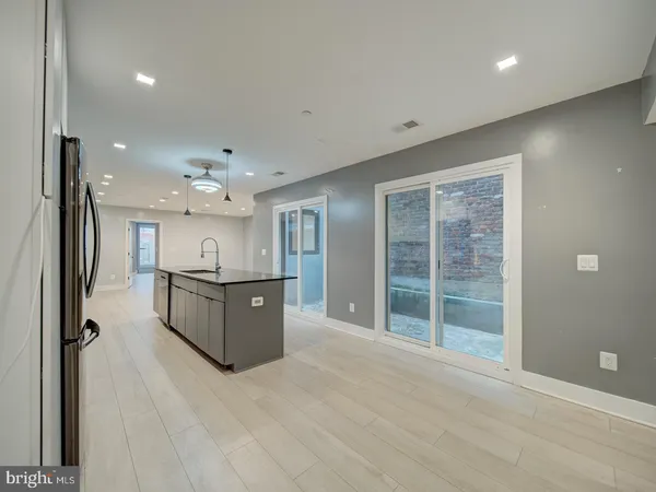 a living room with stainless steel appliances kitchen island furniture and a large window
